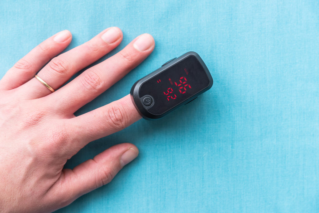 Close-up of adult woman's hand wearing pulse oximeter to measure blood oxygen saturation