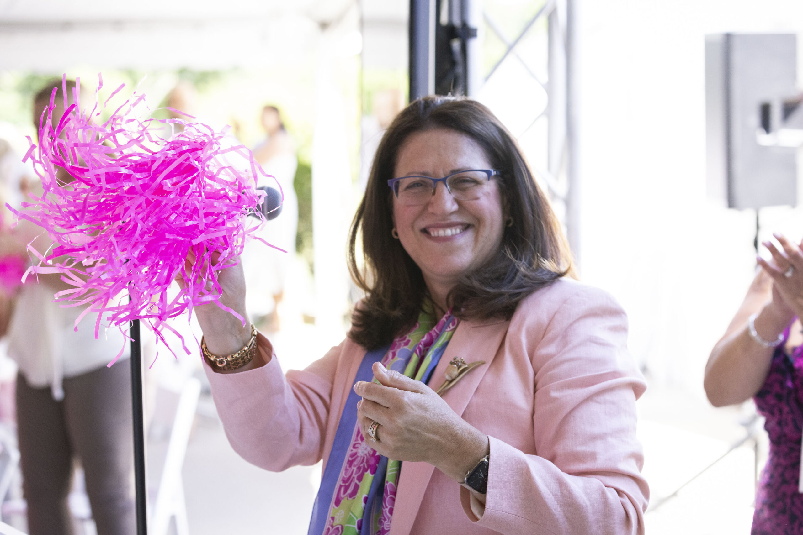 Dr. Generosa Grana holding a pink pom-pom Pink Roses Teal Magnolias event.