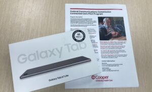 Galaxy Tab A7 Lite tablet box and an informational sheet about the Federal Communications Commission Connected Care Pilot Program are shown on a table.